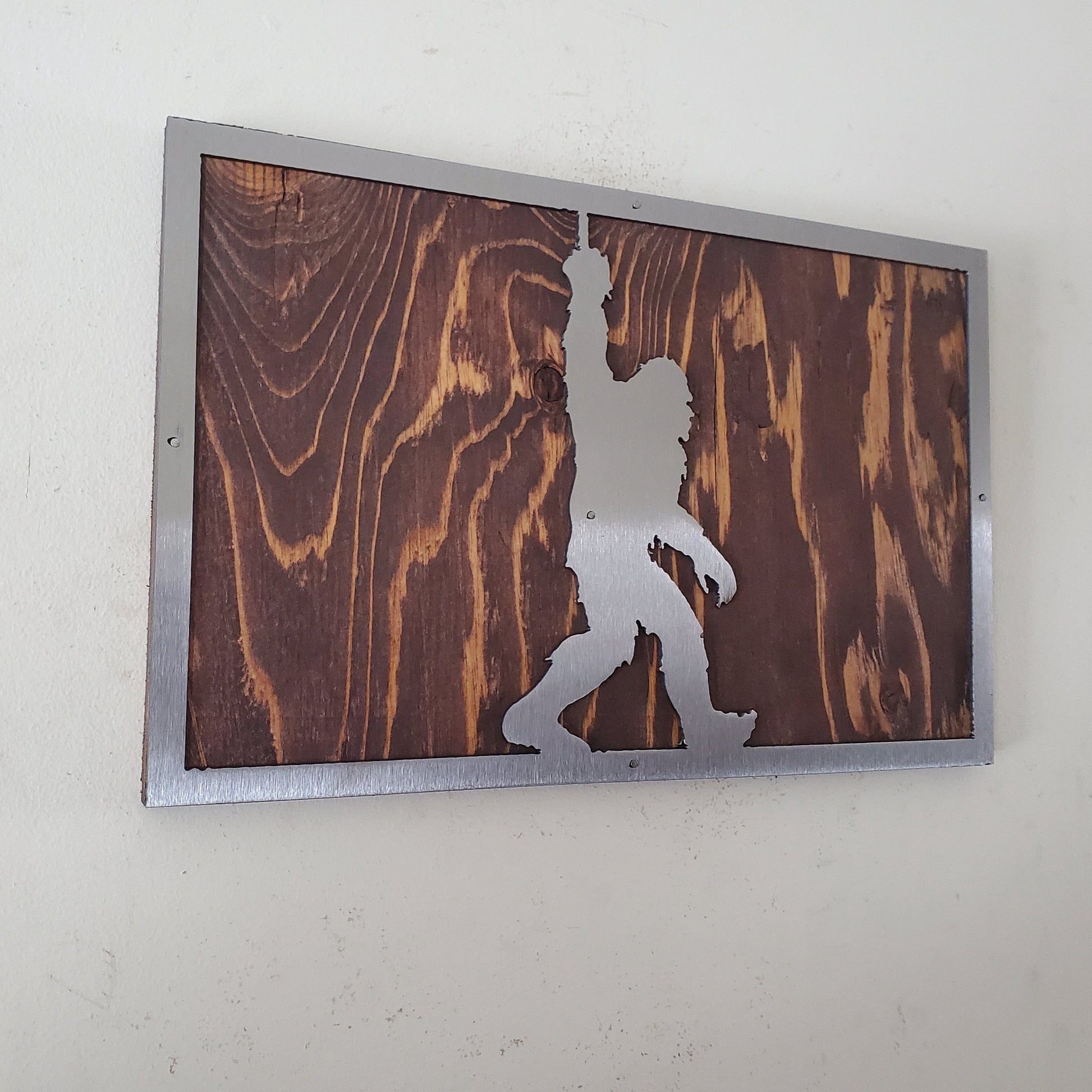 A unique metal art sculpture of bigfoot, mounted on a wooden background. The sculpture is made of high-quality metal and features a realistic design that captures the essence of the mythical creature.